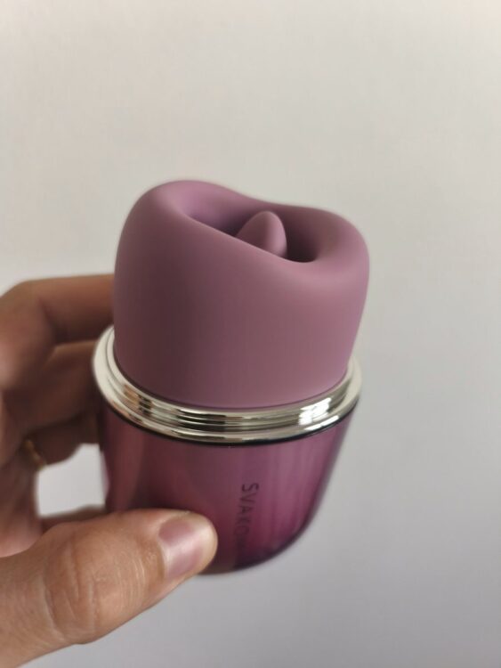 Detalle de la cabeza de silicona del Klitty de SVAKOM sujeto con la mano, mostrando la lengua interior